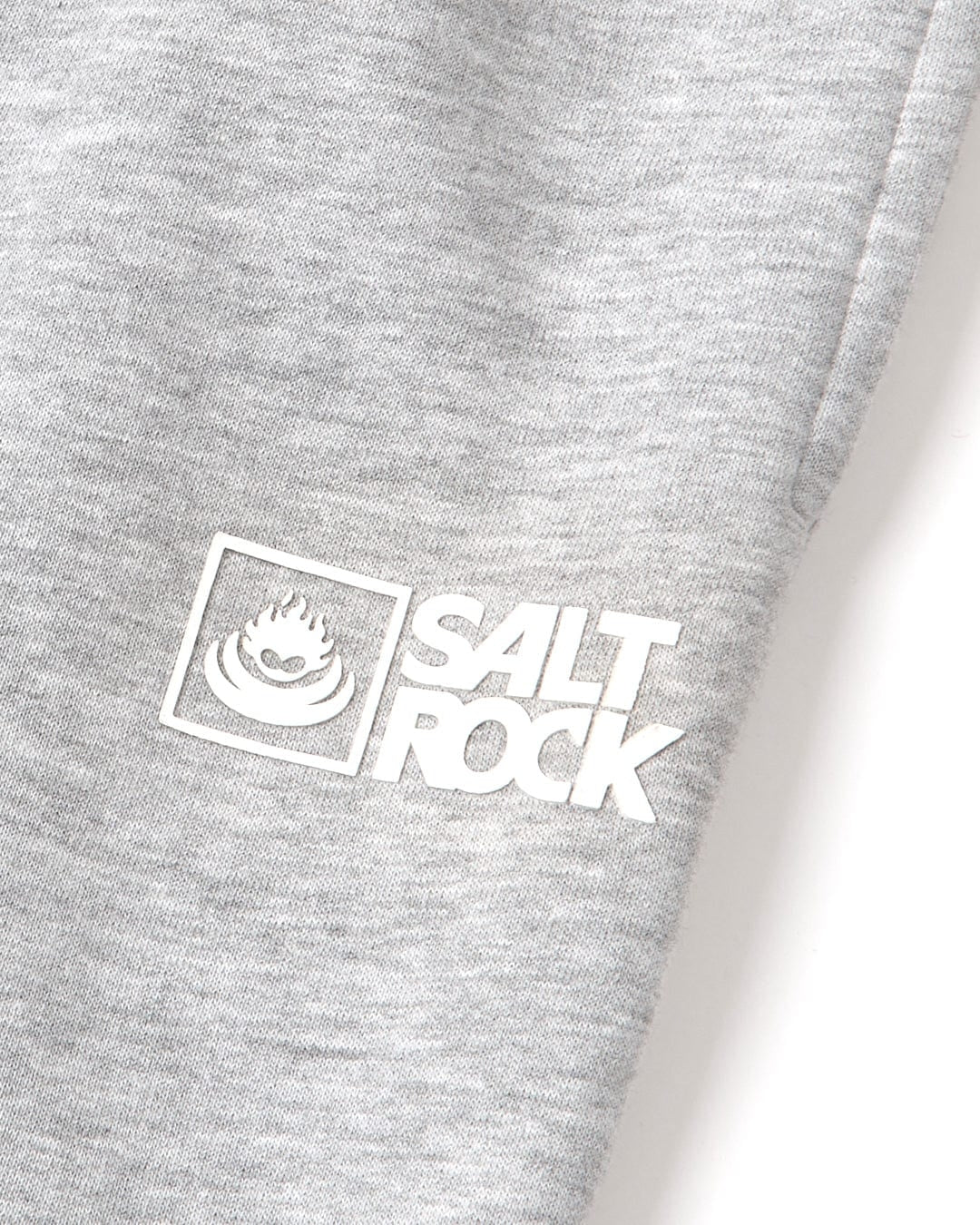Close up of a white printed Saltrock logo on a pair of grey mens Original jogger sweat trousers on a white background