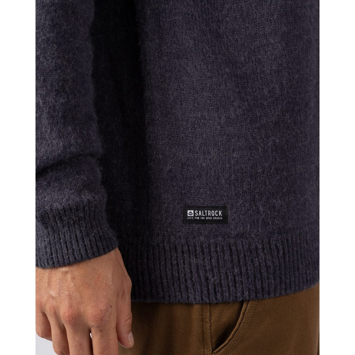 Close-up view of the small logo label on a mens Saltrock Fairisle Rock crew neck knitted jumper in blue.