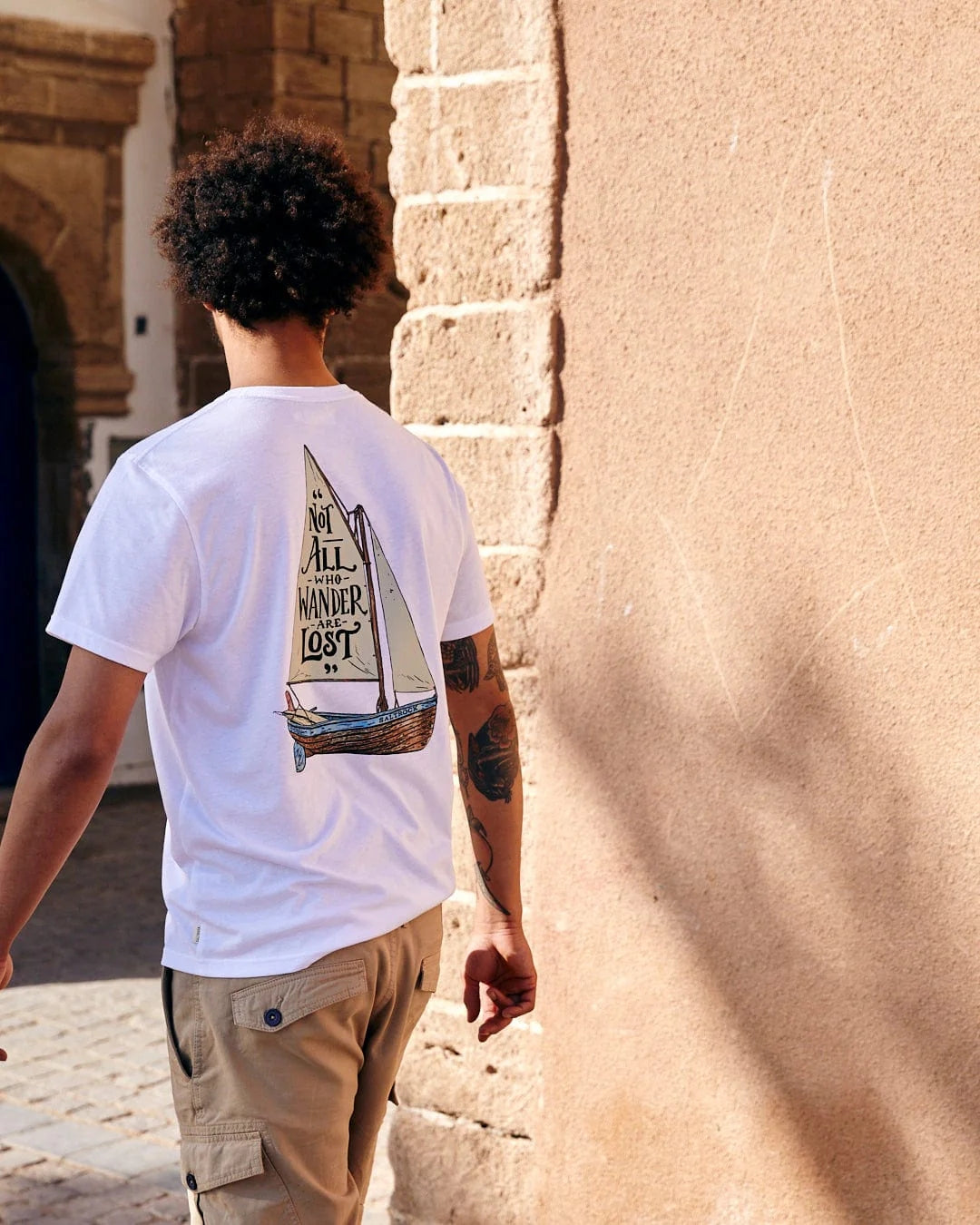 Saltrock mens lost ships tee white t-shirt with sailboat graphic worn by man walking outdoors