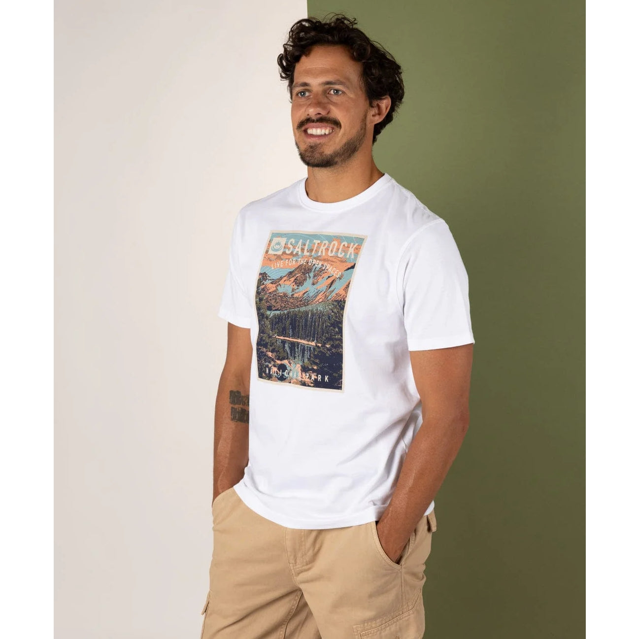 Man wearing a white Saltrock t-shirt with a graphic design, standing against a plain background