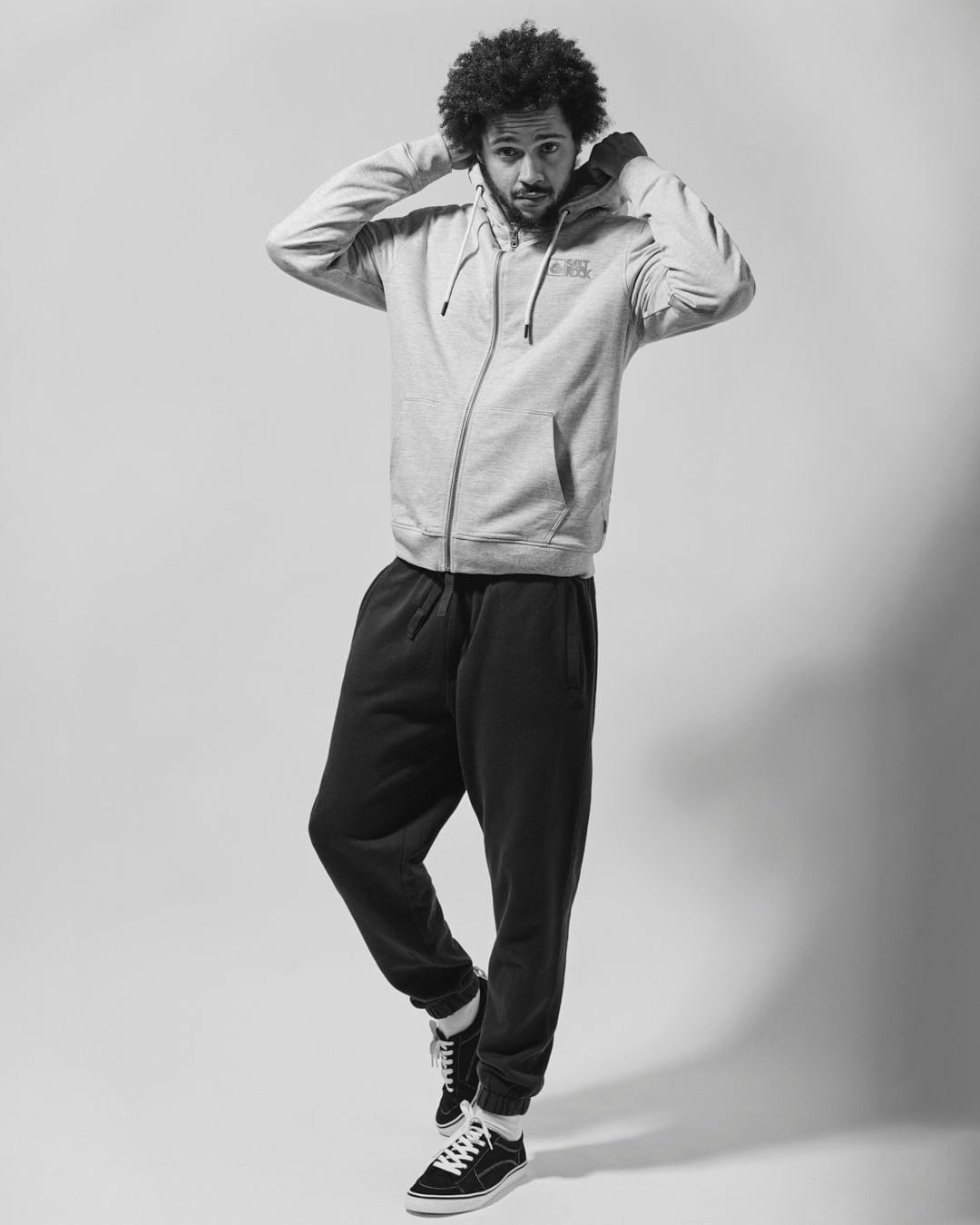 Man wearing a pair of Saltrock Original jogger sweat trousers in black, with a grey hoodie on a white background.