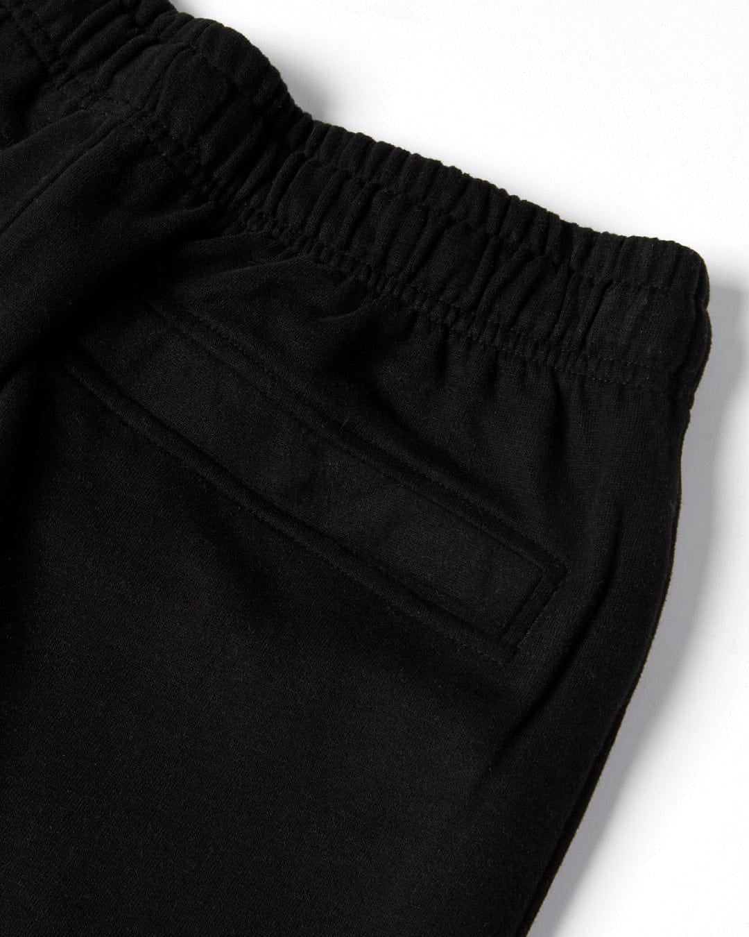 Close up of a back pocket and elastic waist of a pair of mens Saltrock black jogger sweat trousers.