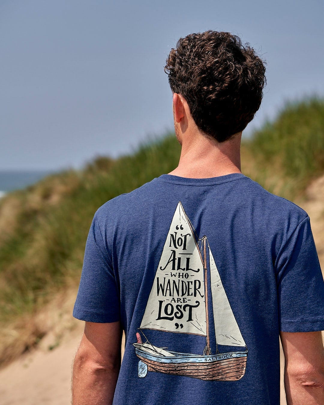 Saltrock mens tee lost ships navy blue with sailboat graphic and quote on back worn outdoors