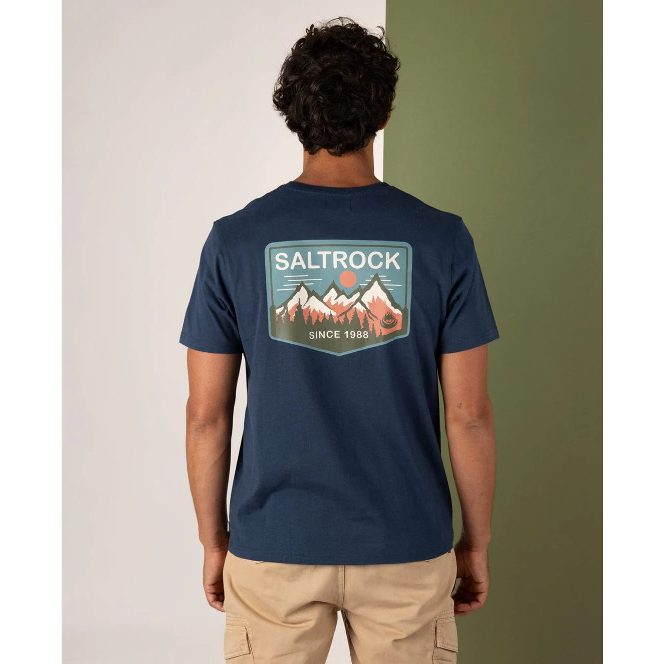 Man wearing a navy blue t-shirt with a 'Saltrock' logo on the back against a neutral background
