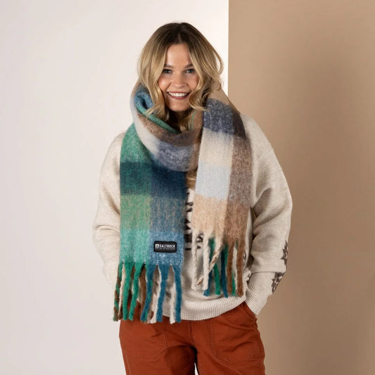 Woman wearing a Saltrock Harvest check pattern scarf in blue, green and brown tones on a beige background