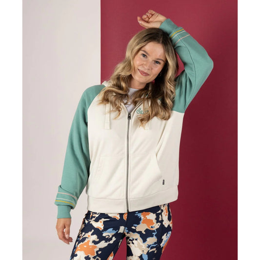 Front view of a woman wearing a Saltrock Links contrast zip hoodie in cream with light blue raglan sleeves on a white and red background.