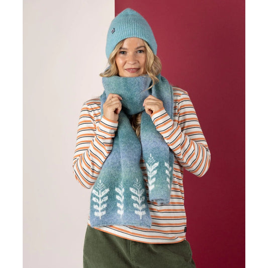 Woman wearing a Saltrock blue knit hat and scarf with a striped shirt against a red and white background