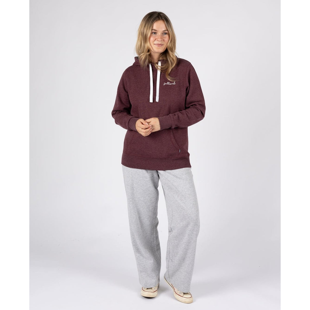 A woman wearing a Saltrock Velator hoodie in Dark Purple, with grey jogger trousers and trainers.