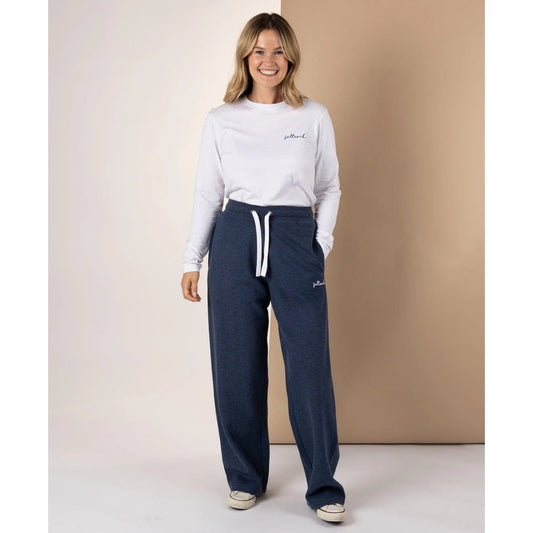 Woman wearing a white sweatshirt and Saltrock Velator sweat trousers in Blue Marl with a logo on a plain background