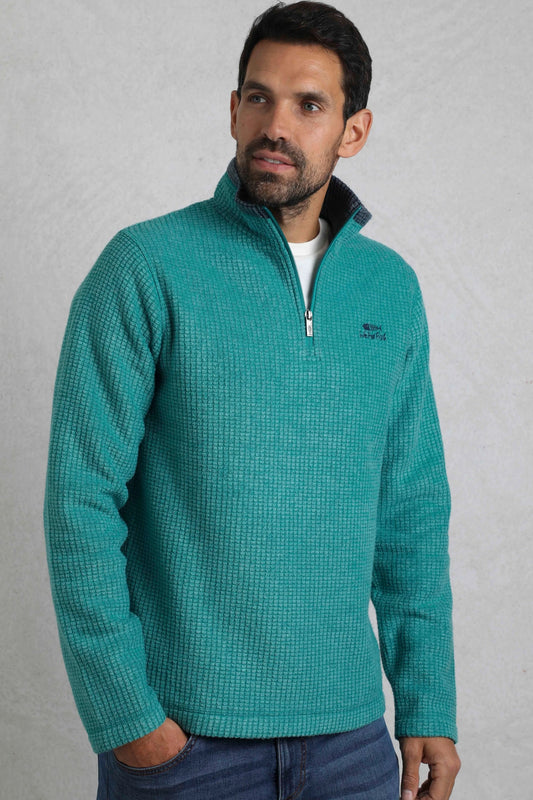 Front view of a man wearing a Weird Fish Viridis teal zip neck grid fleece on a white background.
