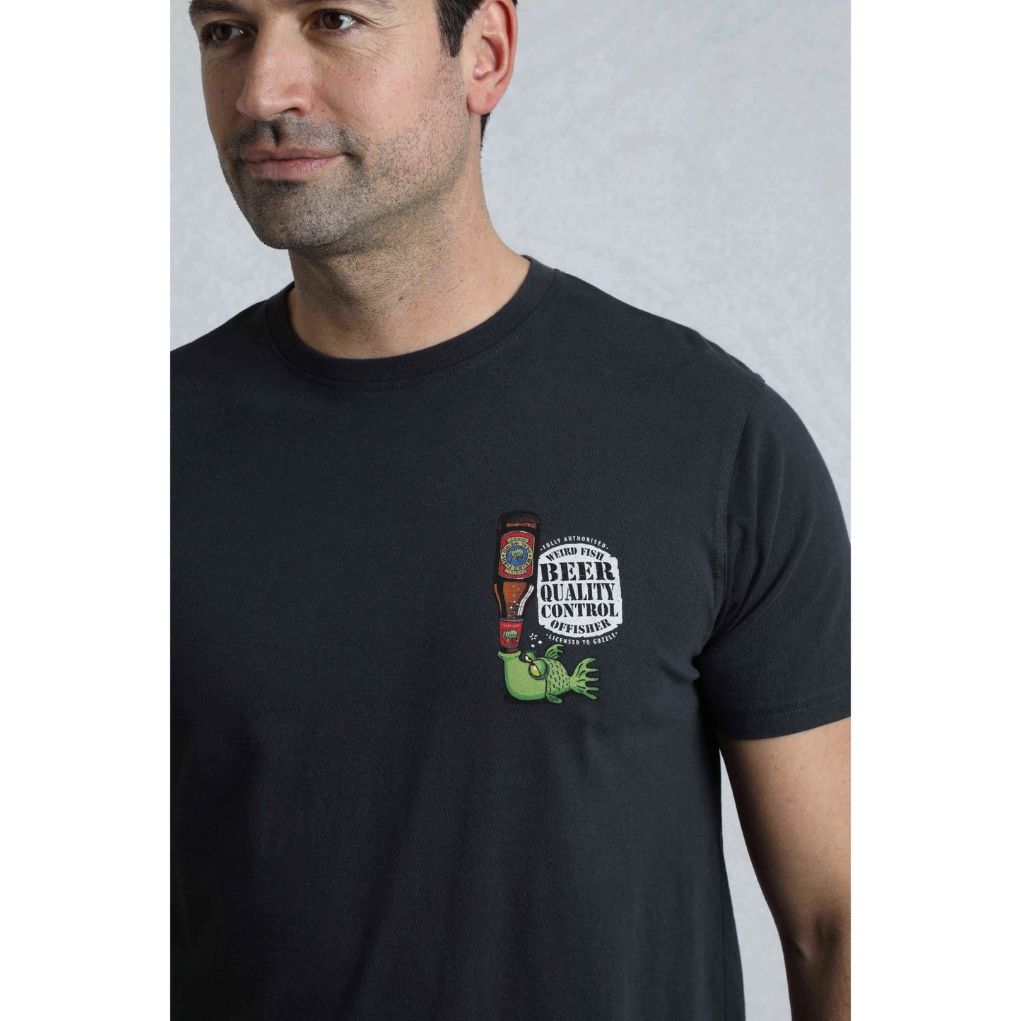Man wearing a black t-shirt with a graphic design on a plain background