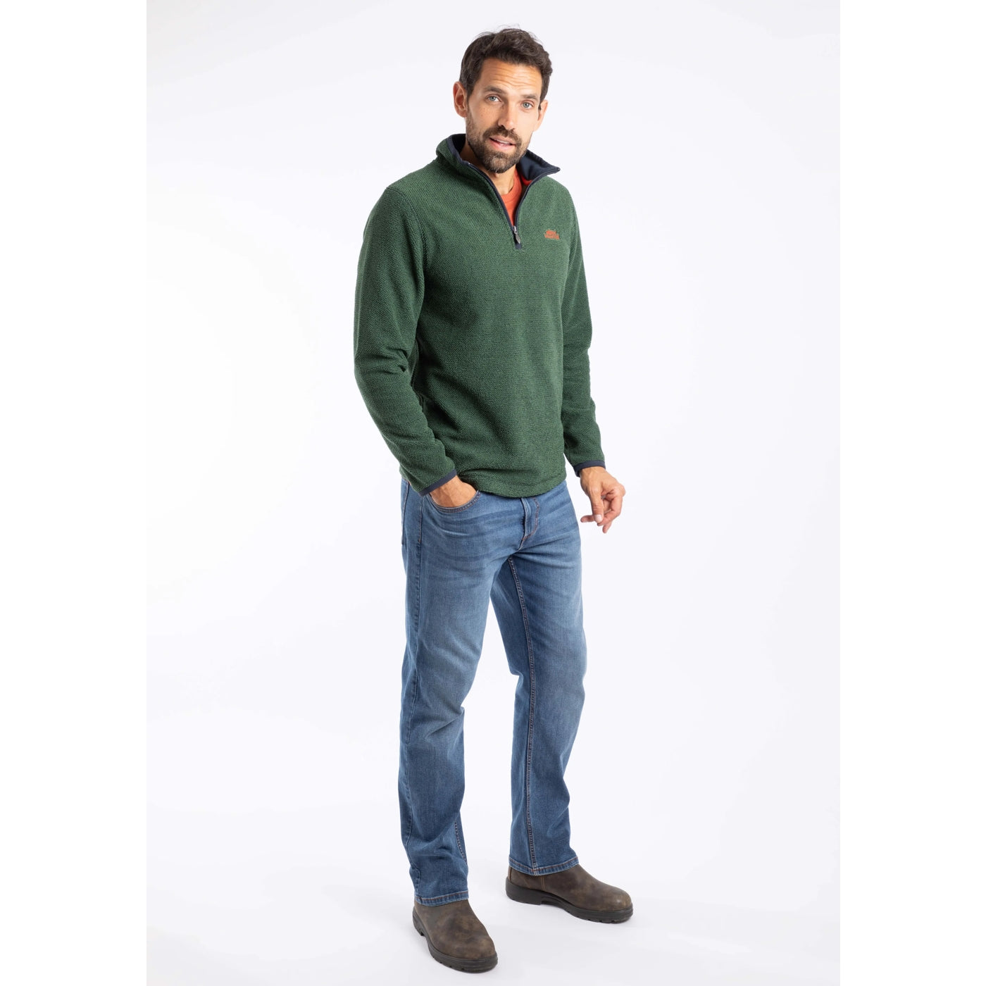 Man wearing a green Weird Fish Errill  pullover fleece and blue jeans on a white background