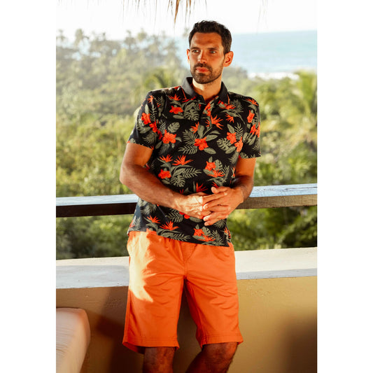 Man wearing Weird Fish mens Murrisk Orange shorts paired with a black floral shirt outdoors