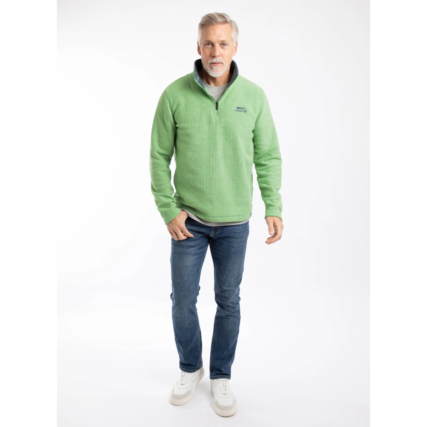 Man wearing a Weird Fish Newark 1/4 zip grid fleece in grass green, with blue jeans and trainers
