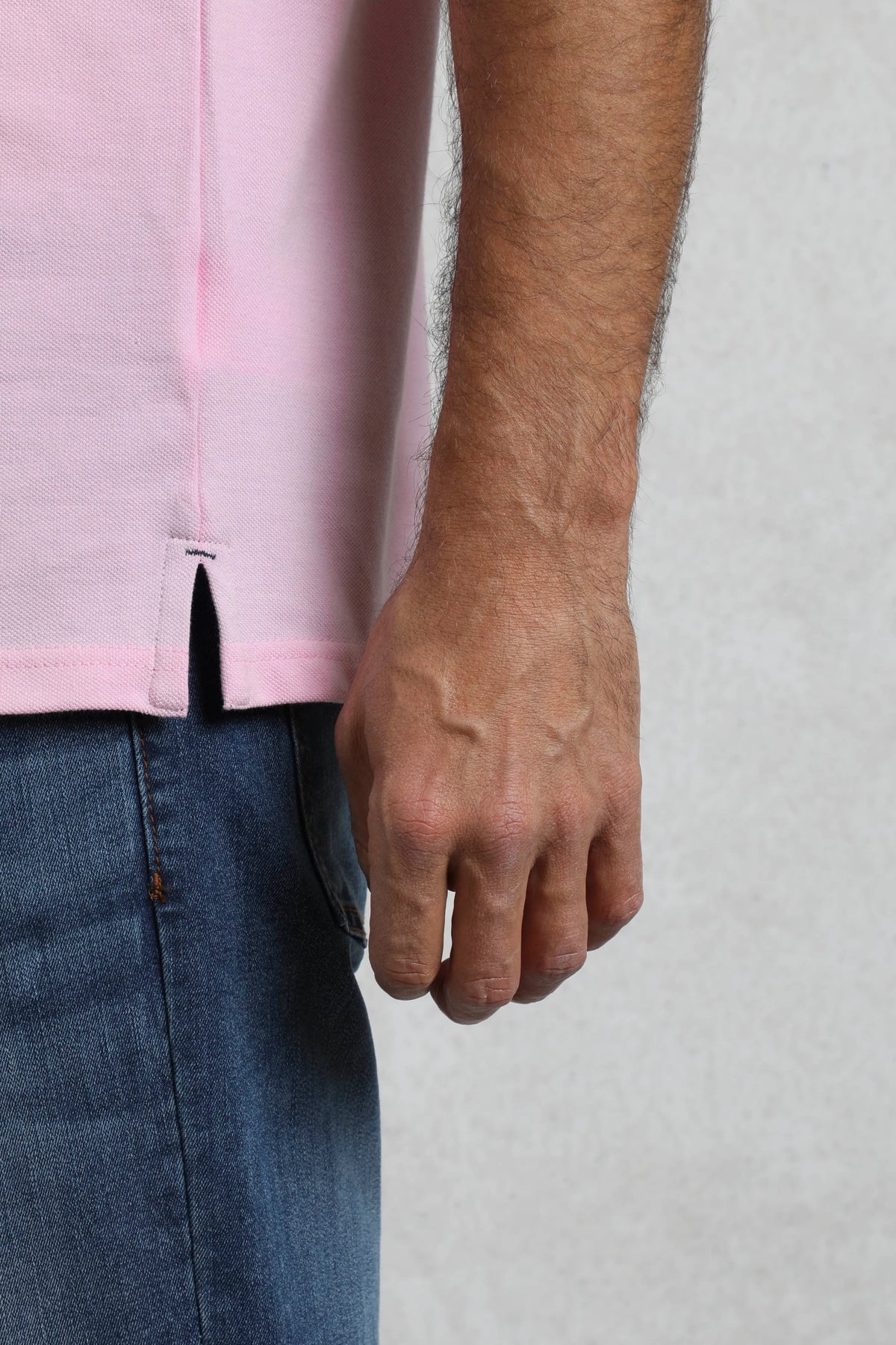 Close-up of Weird Fish mens pink polo shirt hem and side slit worn with blue jeans
