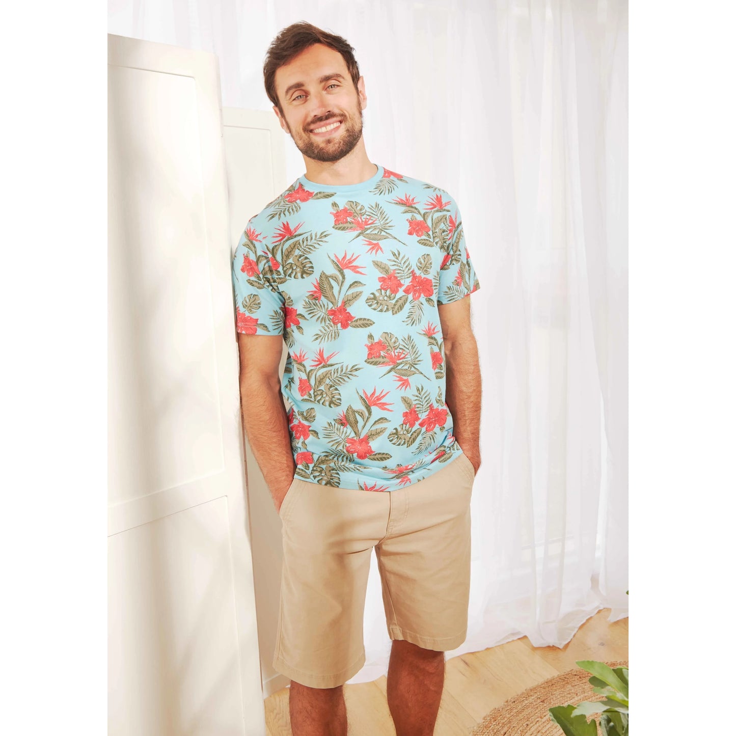Weird Fish mens Rayburn chino shorts Taupe Grey worn by man with floral t-shirt standing indoors