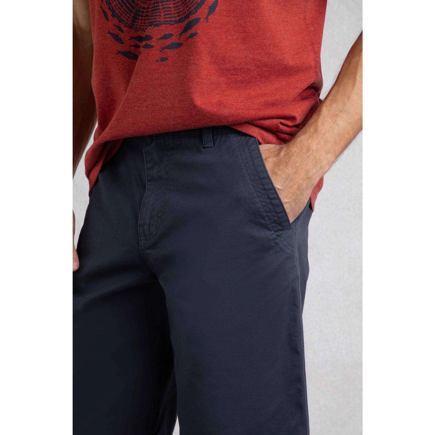 Close-up of Weird Fish mens Rayburn navy chino shorts worn with a red graphic t-shirt showing pocket detail
