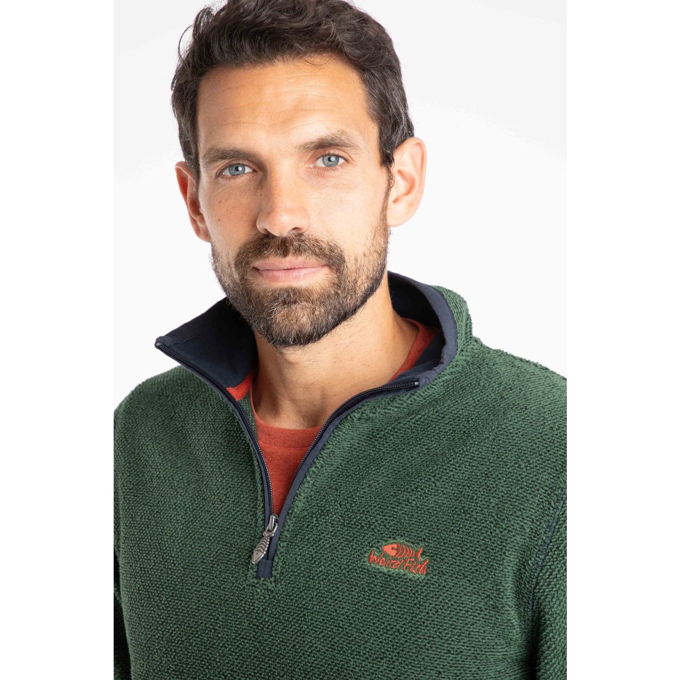 Man wearing a green Weird Fish Errill fleece pullover with a logo on a white background