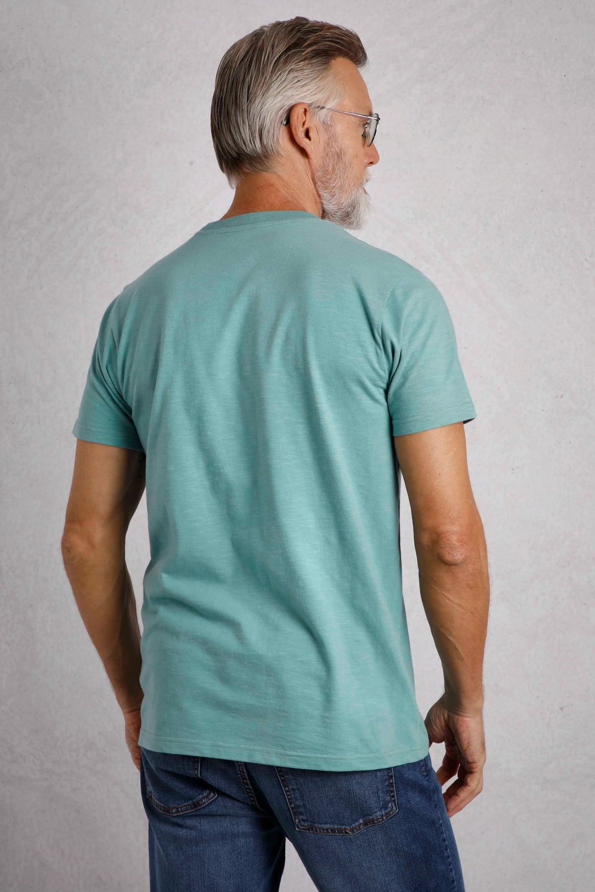Back view of man wearing a light blue Weird Fish mens t-shirt blue paired with jeans