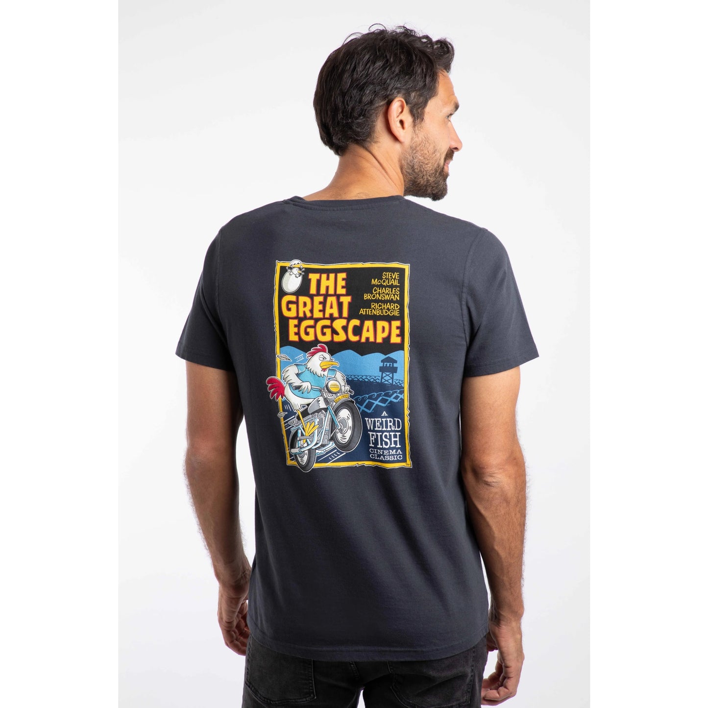 Man wearing a navy t-shirt with a colorful graphic on the back, set against a white background