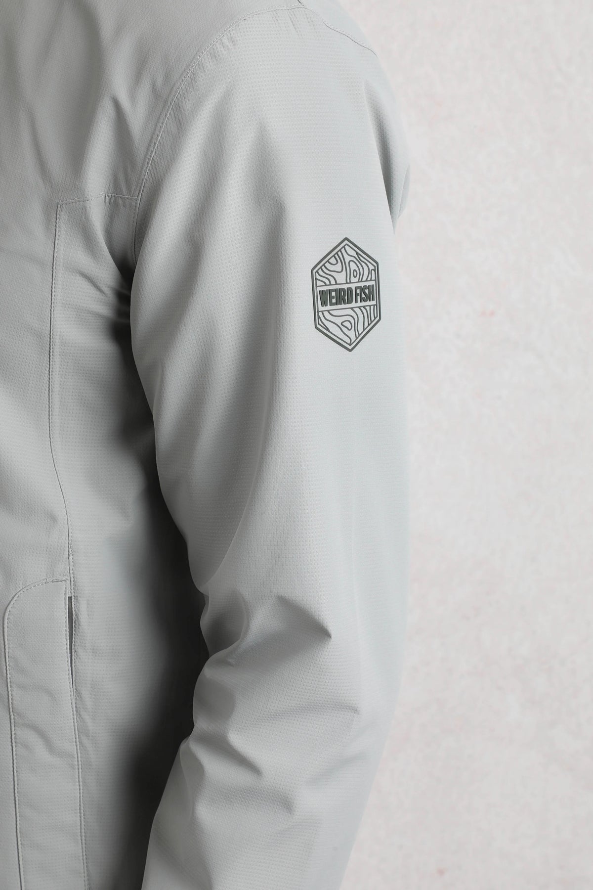 Close-up of Weird Fish mens waterproof jacket grey showing arm and logo patch