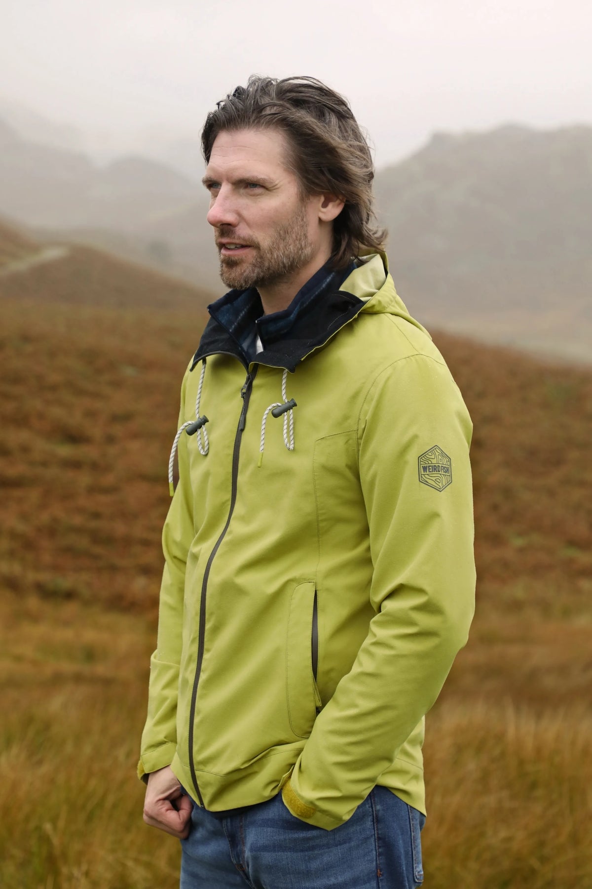 Weird Fish mens waterproof jacket tarragon in green worn outdoors with zip and hood