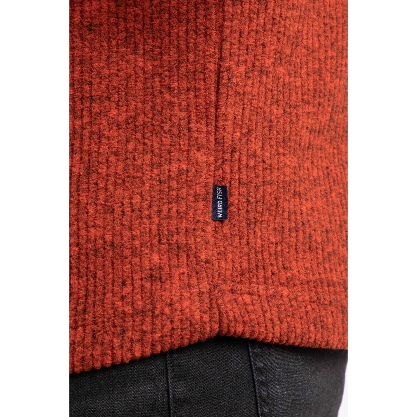 Close-up of a rust red Newport fleece with a Weird Fish brand label on a white background