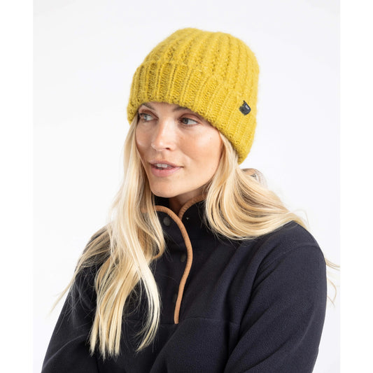 Woman wearing a Weird Fish Clare knitted beanie in Antique Moss yellow with a black logo on a white background