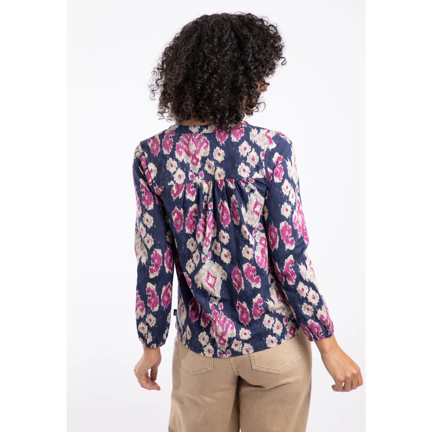 Back view of a woman wearing a Weird Fish blue and pink abstract long sleeve Brooke top on a white background