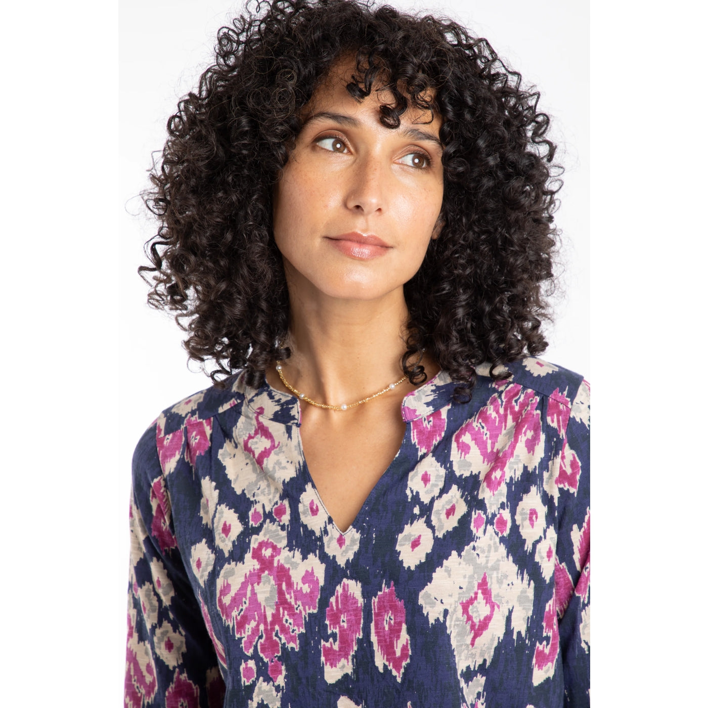 Woman wearing a Weird Fish Brooke blue and pink abstract patterned long sleeve top with a white background