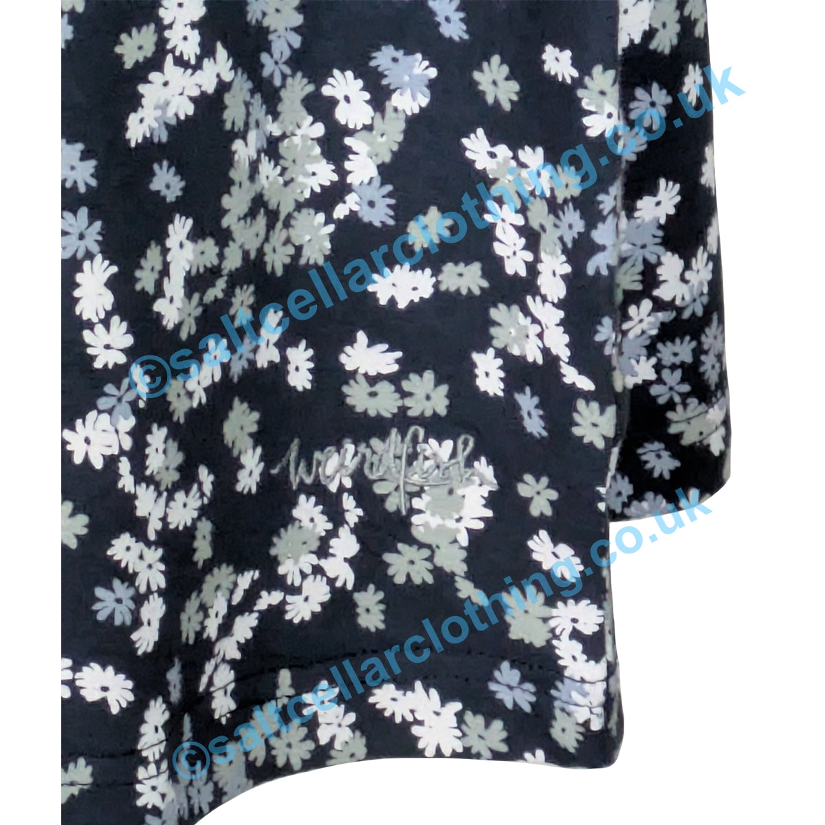 Close up of a the hem of a Weird Fish womens Cassandra dress in Ink Navy with a ditsy floral pattern with an embroidered logo