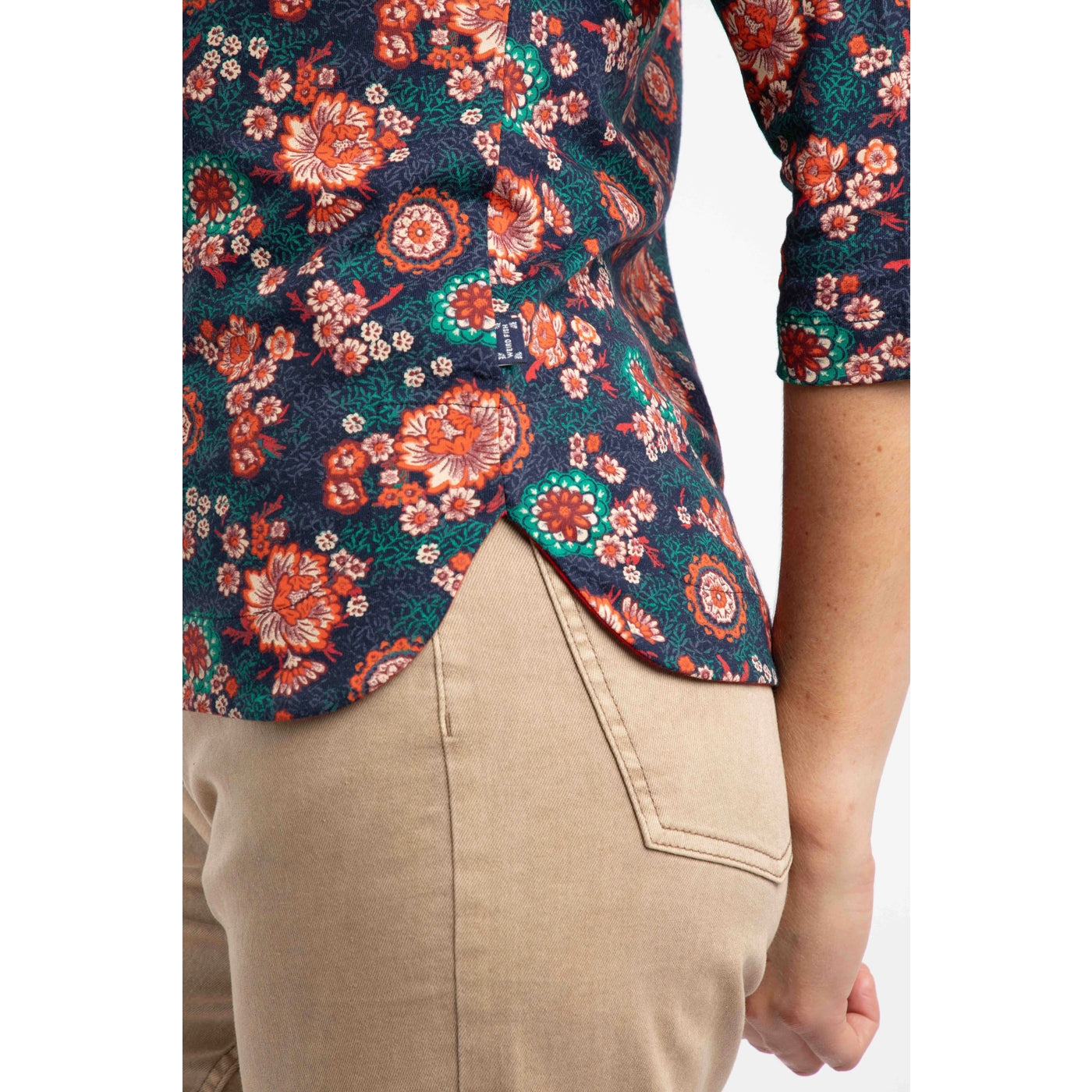 Floral patterned three quarter sleeve t-shirt with a person wearing beige pants on a white background