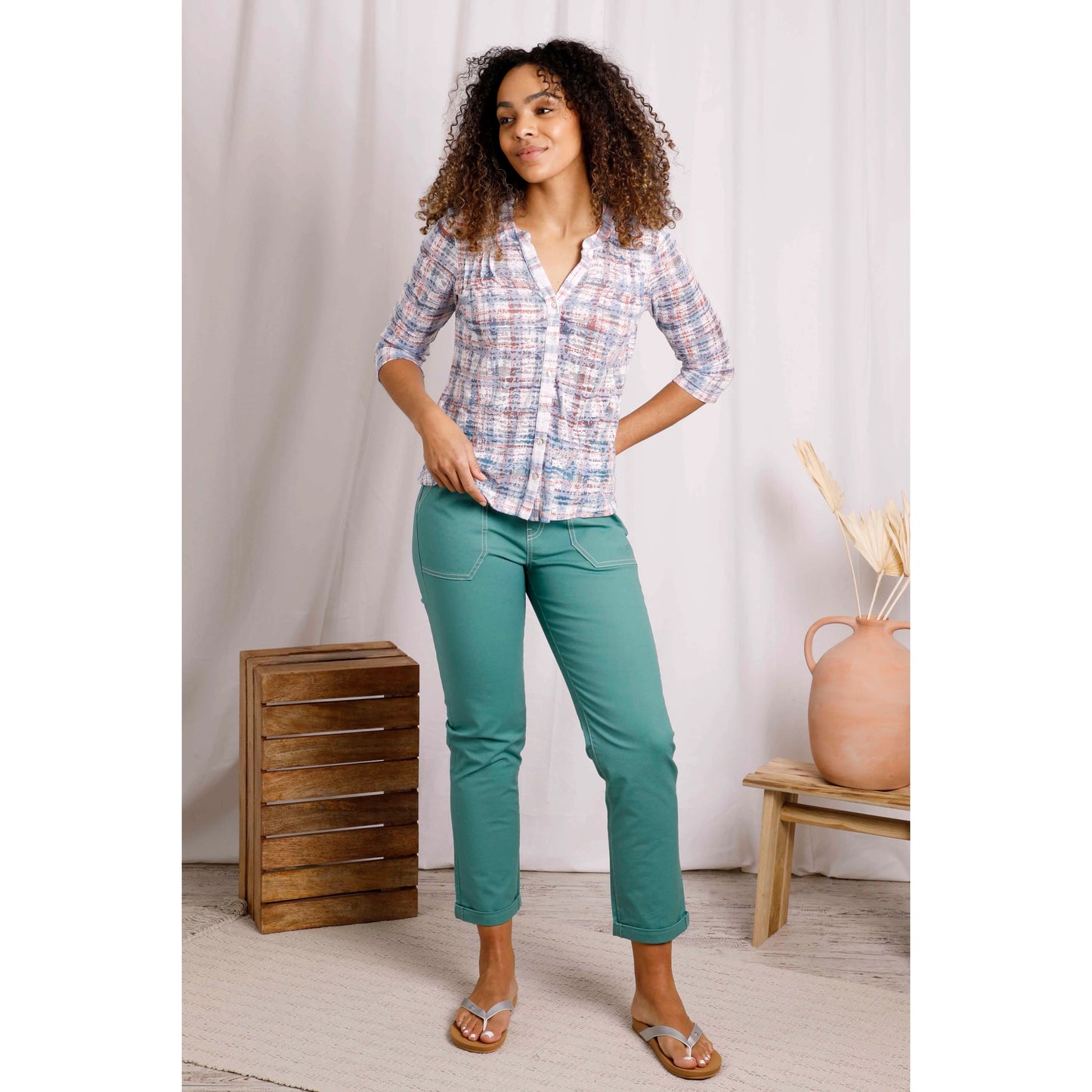 Woman wearing Weird Fish womens Fes check shirt in Pale Denim Blue with green pants and sandals in casual indoor setting