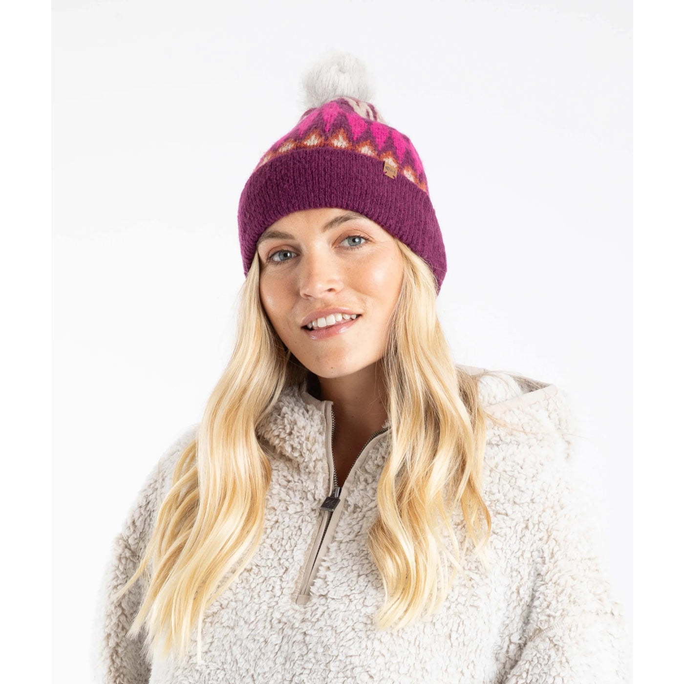 Woman wearing a beet purple Weird Fish Frady knitted beanie with a Fair Isle pattern and a faux fur pom-pom on a white background