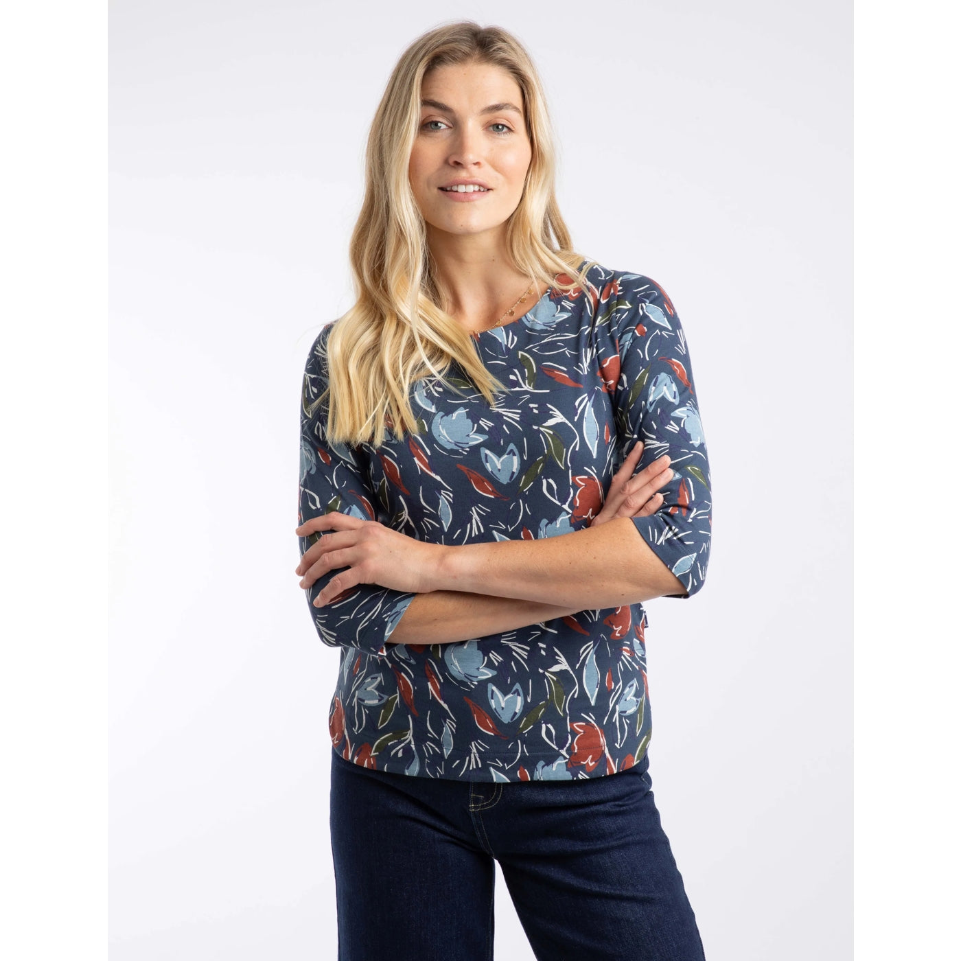 Woman wearing a Weird Fish blue floral patterned three quarter sleeve t-shirt with arms crossed on a white background