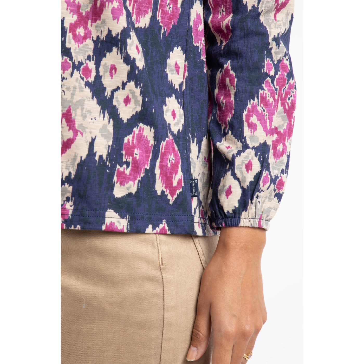 Close-up of a woman wearing a Weird Fish blue and pink purple abstract patterned Brooke top with a brand logo label.