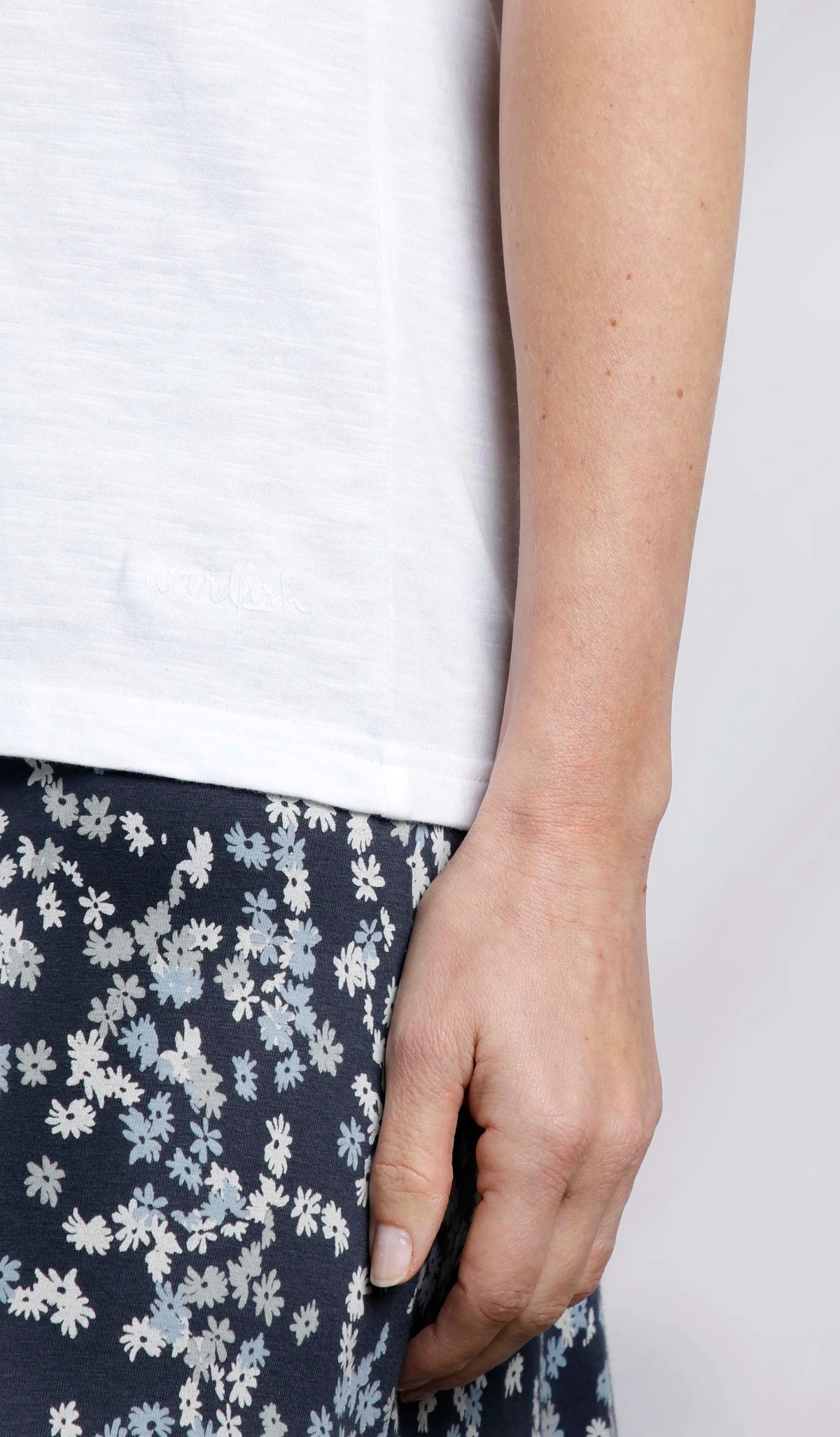 Weird Fish womens Teya t-shirt in White. Close up of hem and side seam on model wearing floral skirt