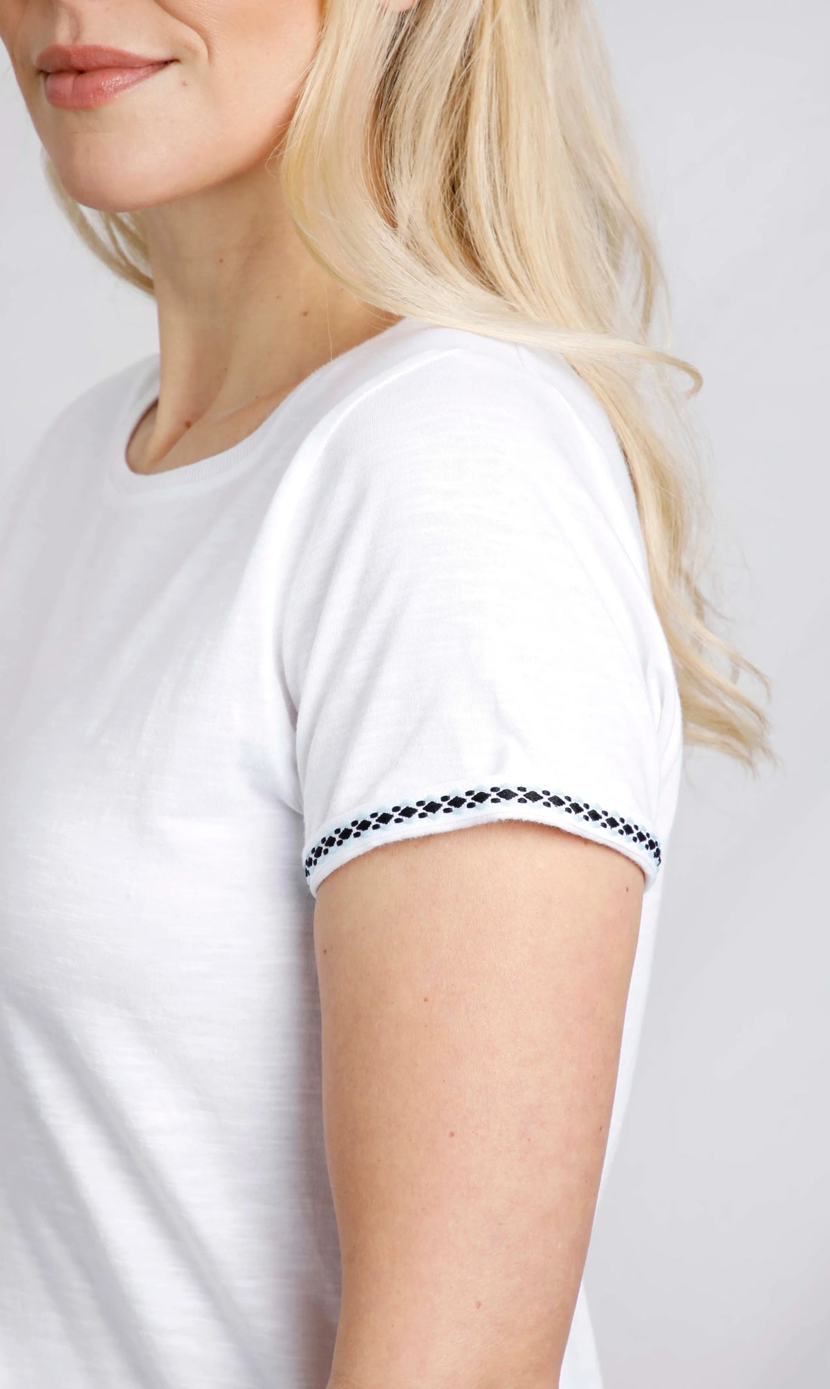Weird Fish womens Teya t-shirt in White. Close up of woman wearing white tee with navy embroidered sleeve trim