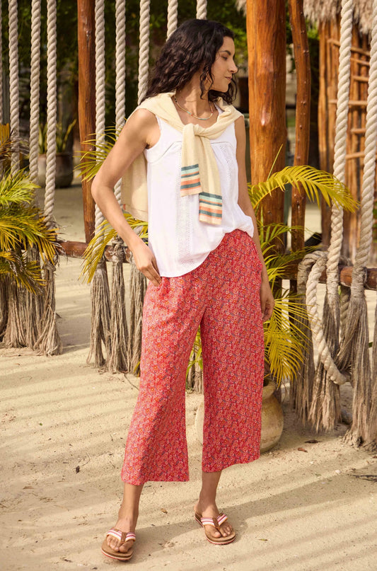A model wearing a pair of women's Weird Fish Sarita wide leg cropped trousers in Tango Red with a floral pattern.