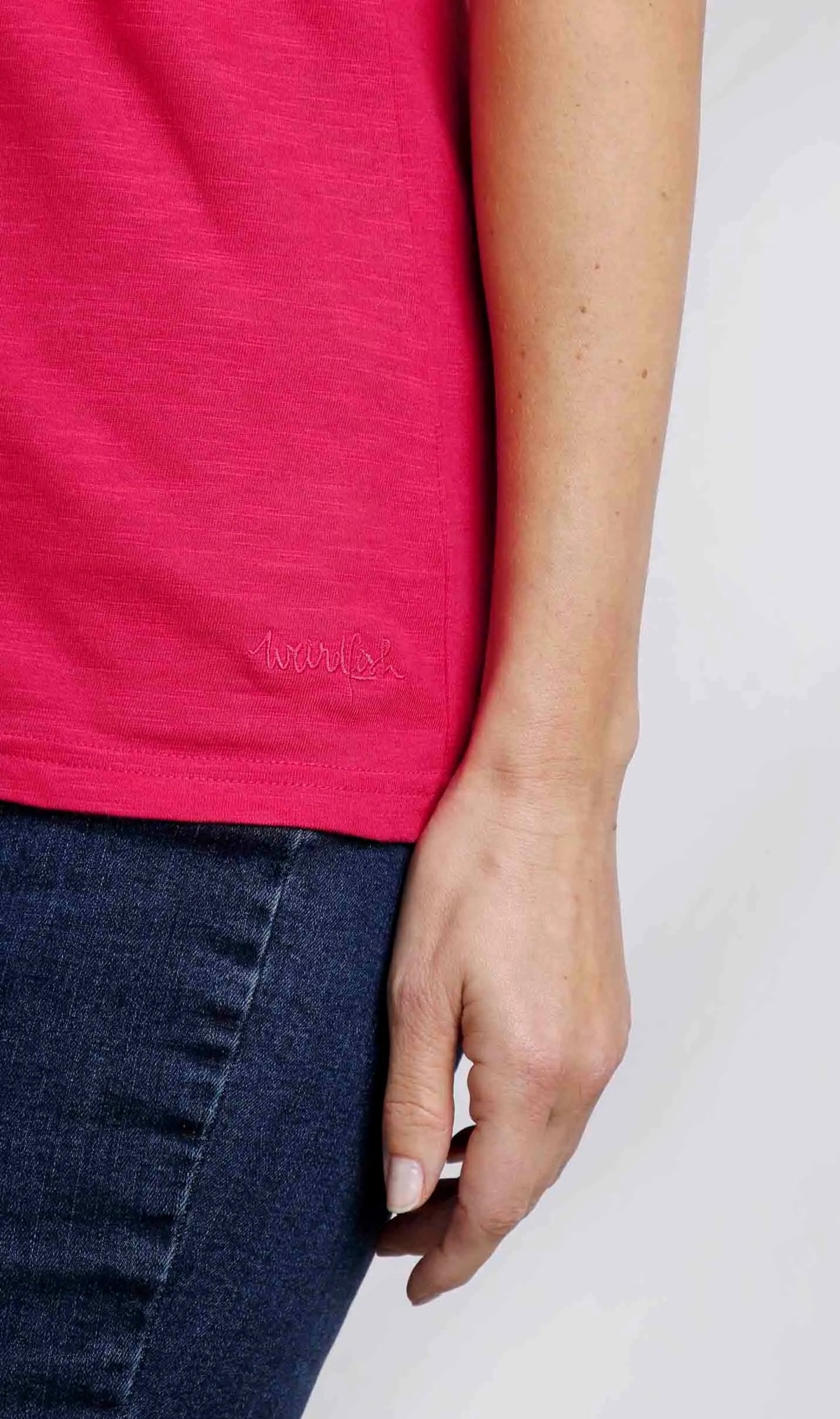 Weird Fish womens Teya t-shirt in Hot Pink showing embroidered hem on model wearing dark jeans and hand by side