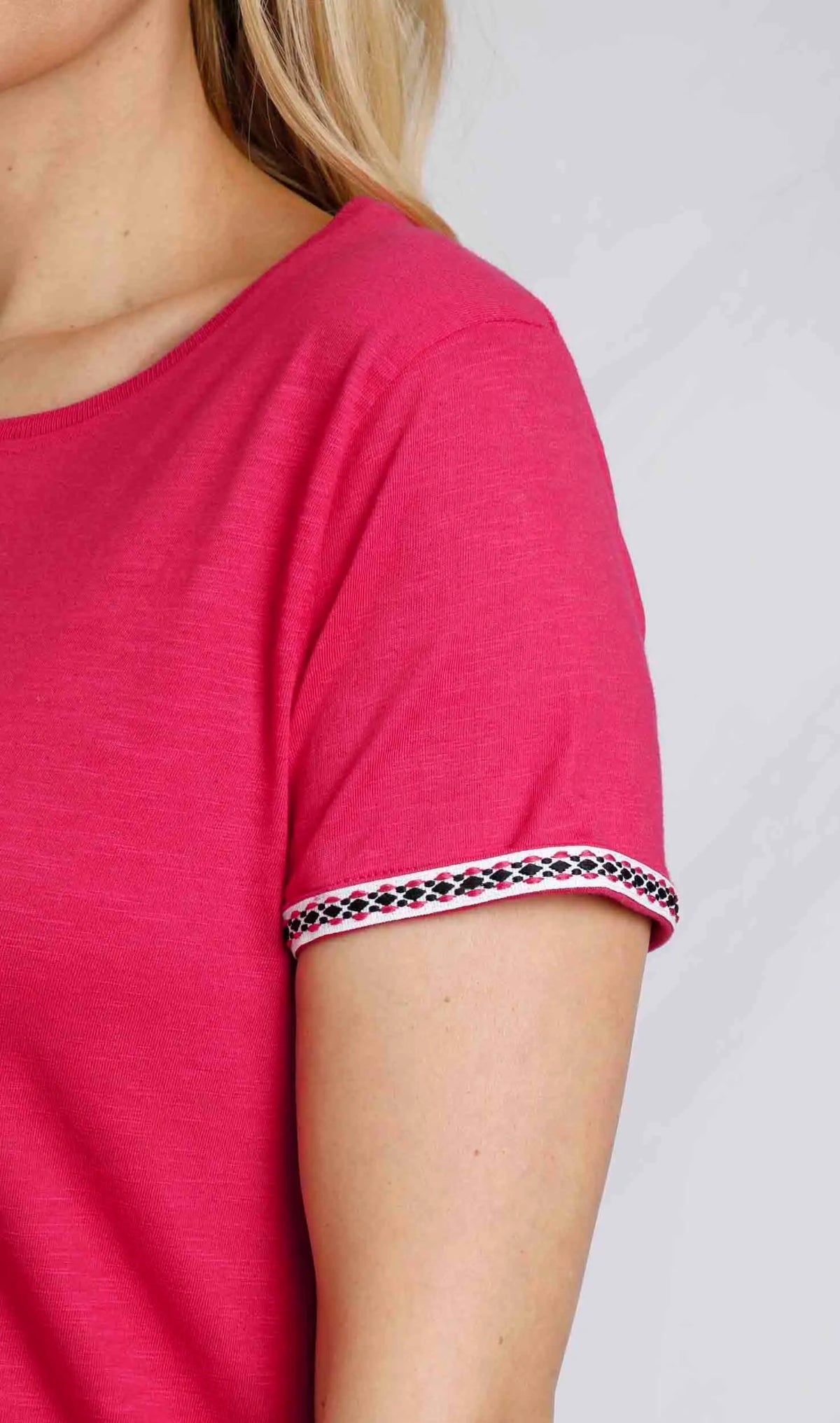Close up of woman wearing Weird Fish womens Teya t-shirt in Hot Pink. Short sleeve with embroidered trim