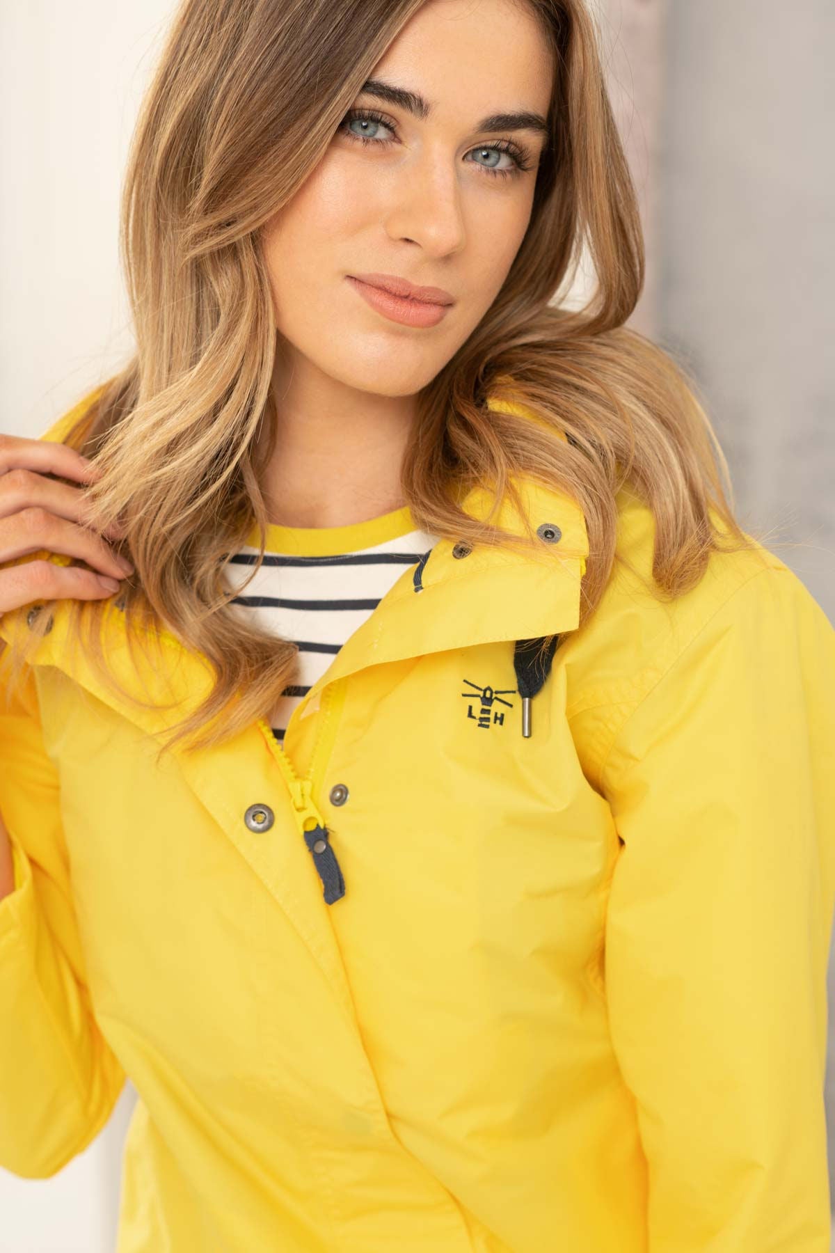 Lighthouse womens jacket yellow worn by woman with striped shirt, featuring hood and zipper details