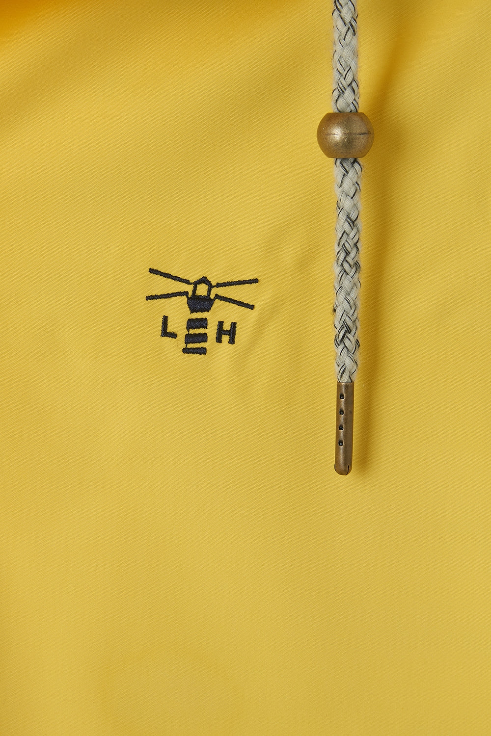 Close-up of Lighthouse yellow waterproof jacket womens logo and drawstring with wooden bead