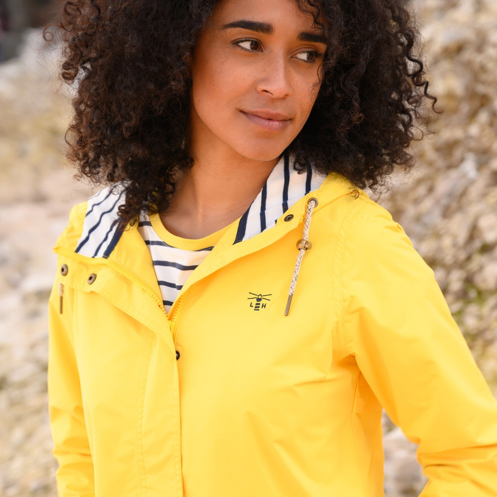 Lighthouse yellow waterproof jacket womens worn by model with curly hair outdoors