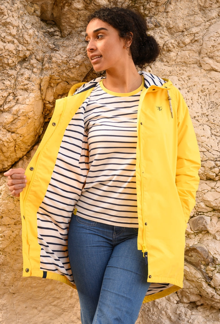 Lighthouse yellow waterproof jacket womens with striped lining worn over striped shirt and jeans outdoors