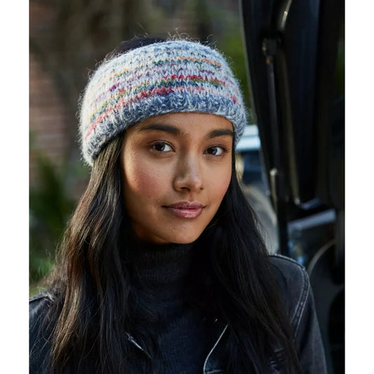 Woman wearing a colourful knitted Pachamama Coroico headband with a blurred background