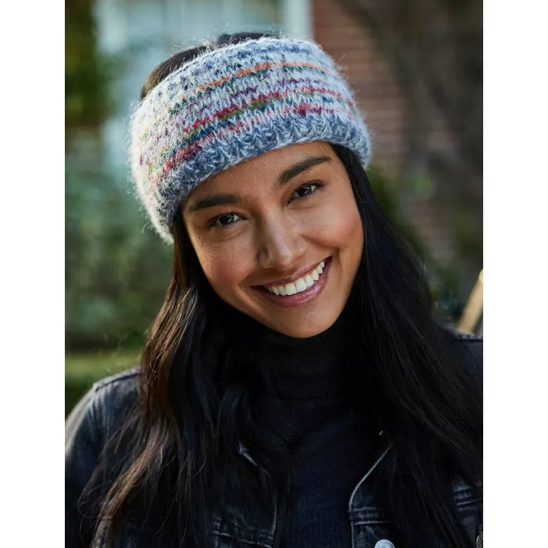 Woman wearing a Pachamama Coroico multicolour stripe knitted headband outdoors