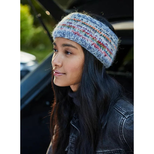 Main view of a woman wearing a colourful knitted Pachamama Coroico headband with a blurred background