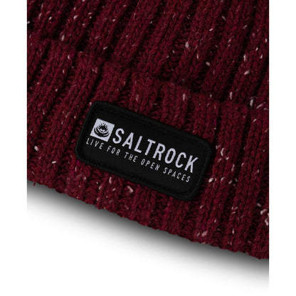 Close-up view of the hem and logo patch of an adults Saltrock Heritage ribbed knit beanie in Burgundy red with a white fleck.