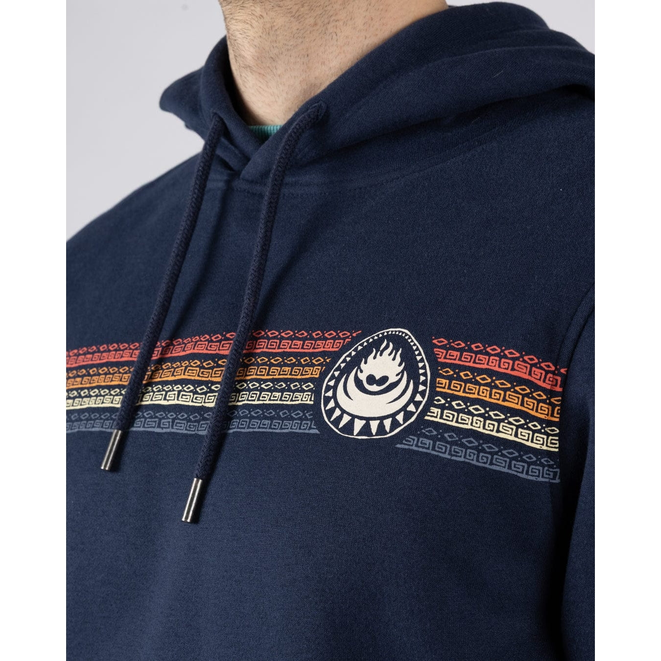 Close-up view of a man wearing a navy blue Saltrock Tribal Stripe pop hoodie with multicolour stripe print and logo on the chest